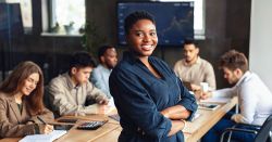 Black woman leaning against a table with colleagues
